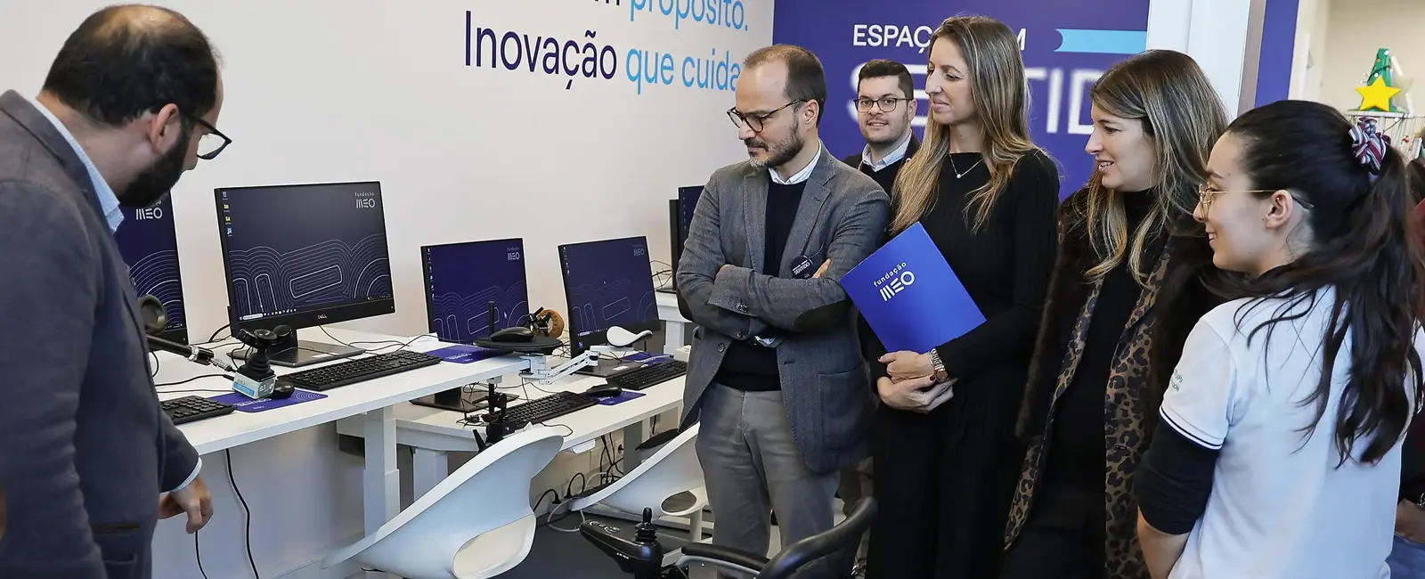 Mesa com tecnologias de apoio e participantes a acompanhar as explicações